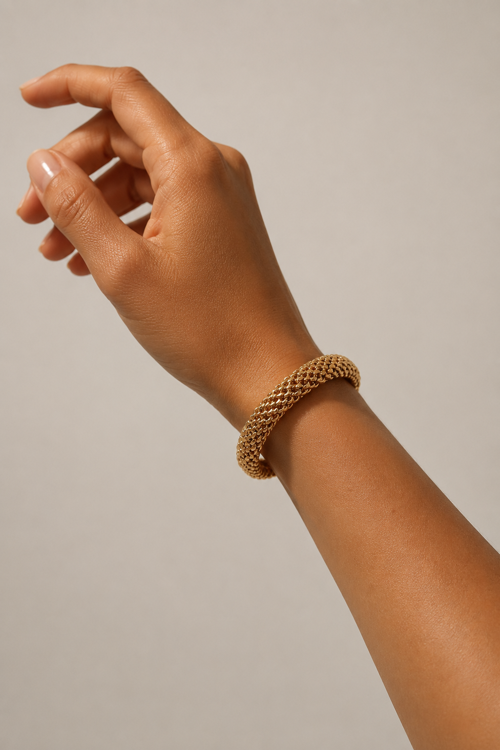 Brazalete de malla dorada puesto en la muñeca